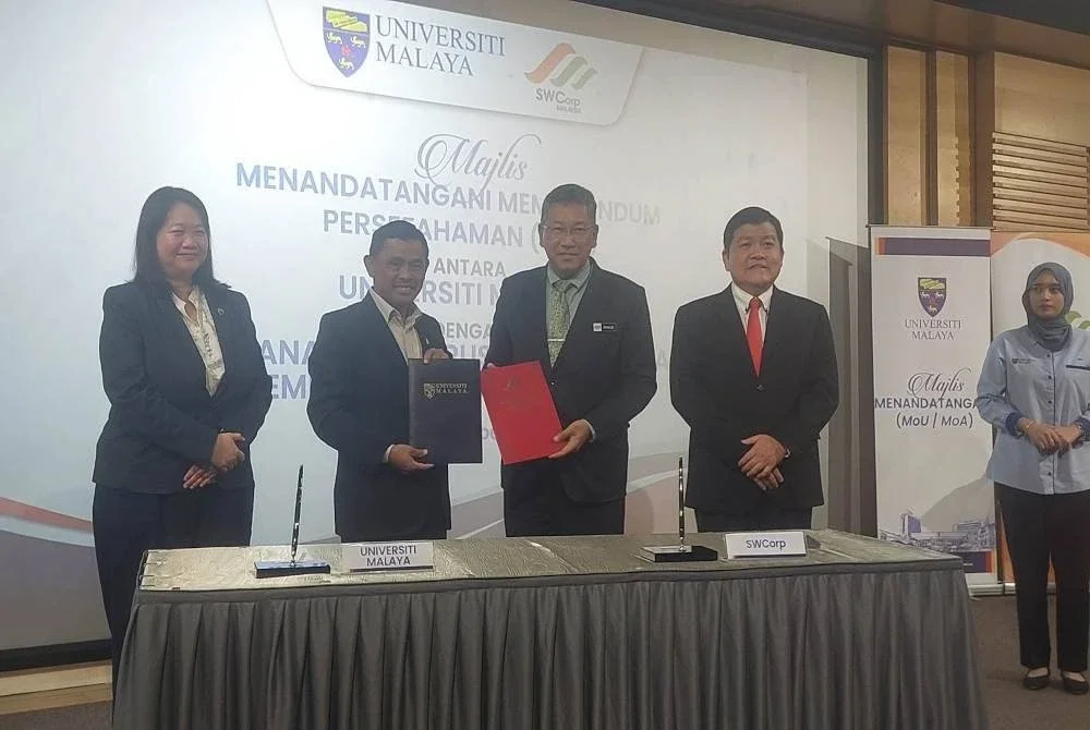 Khalid (tiga dari kanan) dan Kaharudin (dua dari kiri) menunjukkan MoU yang telah ditandatangani di Dewan Auditorium, UM pada Rabu.