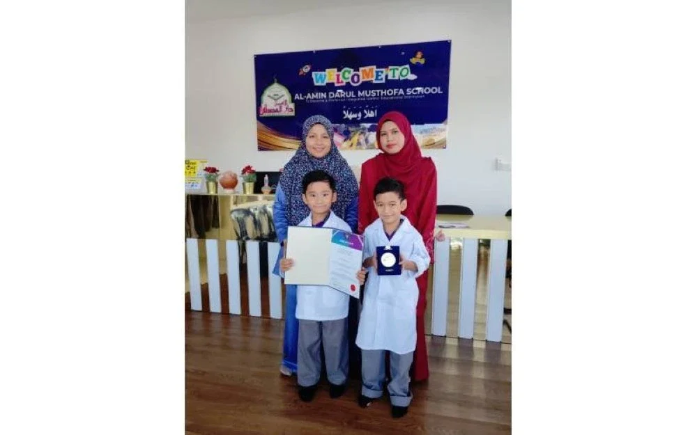 Mohamad Mika dan Aqeef Shareef menunjukkan sijlil dan pingat yang dimenangi mereka sambil ditemani dua guru.