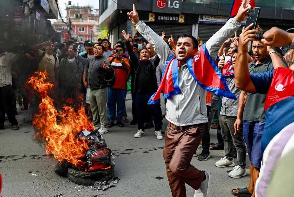 Penunjuk perasaan membakar tayar sambil mengibarkan bendera kebangsaan Nepal di Kathmandu pada 9 September 2025, sebagai bantahan terhadap tindakan keras polis yang mengorbankan sekurang-kurangnya 19 orang sehari sebelumnya.