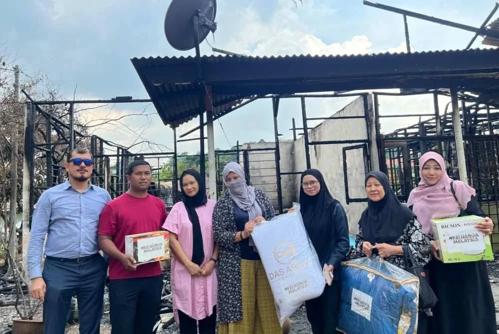 Azlina Rosdy (tiga dari kanan) menyampaikan sumbangan Yayasan Keluarga Malaysia kepada Norfazilah (empat dari kiri) semasa menziarahinya selepas rumah didiami di Kampung Sungai Penchala di sini musnah terbakar pada Selasa.