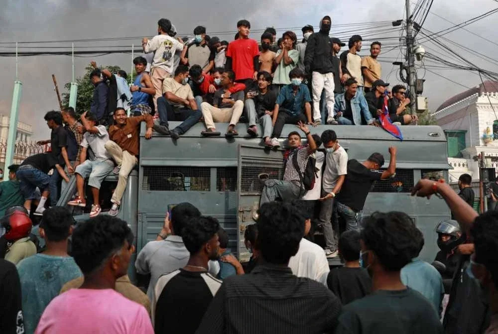 Penunjuk perasaan berkumpul di atas kenderaan keselamatan di luar Singha Durbar, bangunan pentadbiran utama kerajaan Nepal, di Kathmandu.