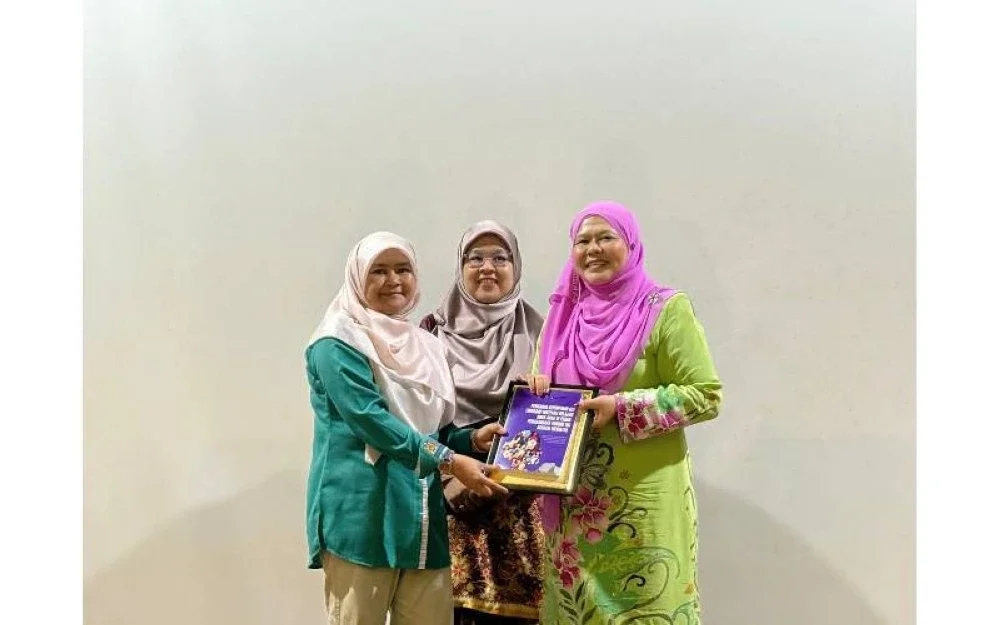 Salbiah (kanan) menerima buku Kajian Pengaruh Kepimpinan Ibu Terhadap Motivasi Belajar Anak-Anak di Perak: Penghargaan Kendiri Ibu Sebagai Mediator daripada Aziah selepas pembentangan kajian berkenaan.