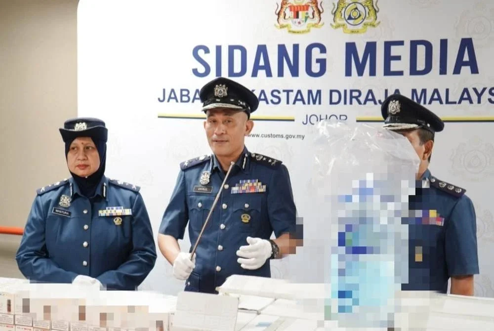 Aminul Izmeer (tengah) menunjukkan air zamzam dan cecair rokok elektronik yang dirampas dengan nilai rampasan keseluruhan termasuk duti serta cukai dianggarkan mencecah RM3.42 juta. Foto JKDM Johor