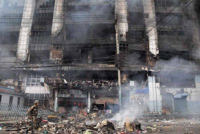 Seorang anggota tentera membuat rondaan di sepanjang jalan ketika asap berkepul-kepul dari bangunan pasar raya yang terbakar di rangkaian runcit terkenal Nepal Bhat-Bhateni. Foto AFP