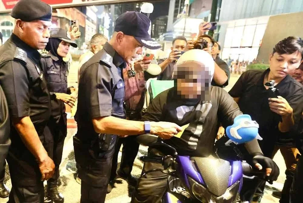 Fadil menyerahkan notis advokasi kepada penunggang motosikal di Jalan Bukit Bintang.