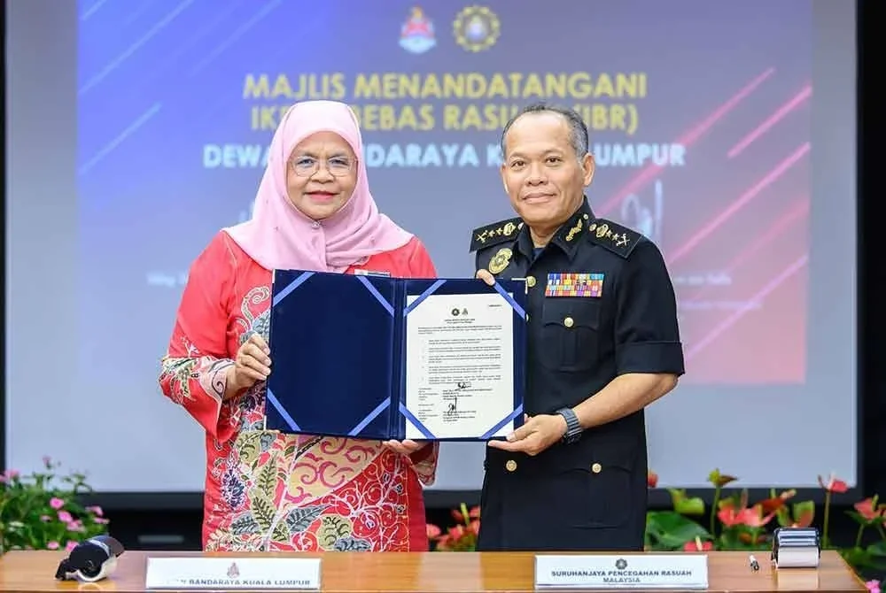 Maimunah (kiri) memegang dokumen Ikrar Bebas Rasuah yang ditandatangani bersama Mohamad Zakkuan di Menara DBKL, Kuala Lumpur.
