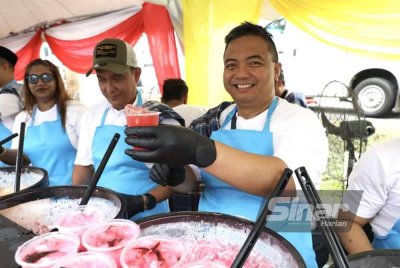 Adam (kanan) turut mengagihkan minuman kepada pengunjung yang singgah ke reruai Air Selangor di sini pada Sabtu. Foto SINAR HARIAN/ ASRIL ASWANDI SHUKOR.