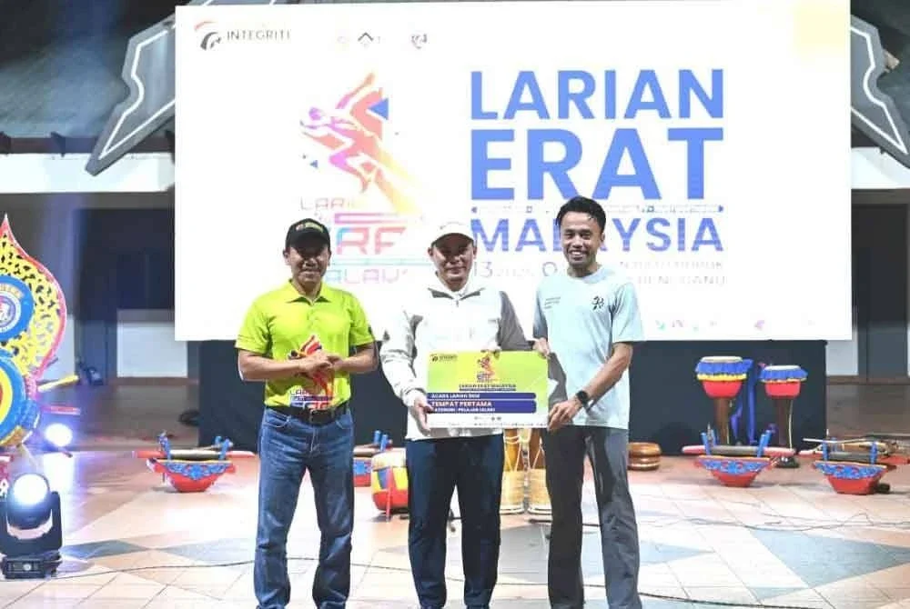 Ismail (kiri) mengiringi Hishamuddin (tengah) menyampaikan hadiah kepada peserta program Larian ERAT yang berlangsung di Dataran Batu Buruk, Kuala Terengganu.