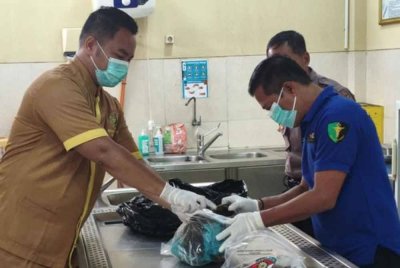 Anggota jabatan forensik hospital memeriksa cebisan mayat wanita yang dikerat 300. - Foto: Agensi