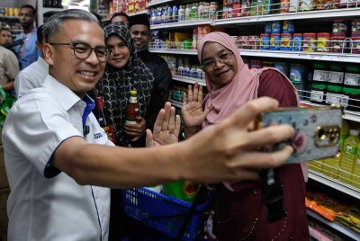 Fahmi berswafoto bersama sebahagian pelanggan ketika melakukan tinjauan perkhidmatan SARA di Kubang Semang. Foto Bernama