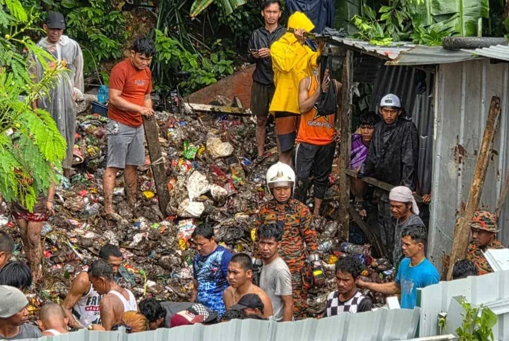 Pasukan bomba dan orang ramai di lokasi kejadian tanah runtuh di Kampung Cenderakasih, Kota Kinabalu. Foto JBPM Sabah