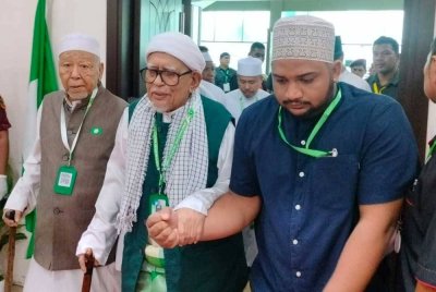 Abdul Hadi (tengah) diiringi Mursyidul Am Pas, Datuk Hashim Jasin ketika berarak memasuki dewan Muktamar.