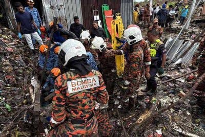 Anggota bomba giat menjalankan operasi mencari mangsa yang tertimbus dalam runtuhan di Kampung Cenderakasih, Kolombong, hari ini. - Foto: Bernama