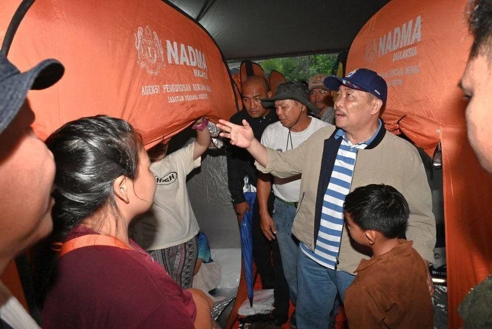 Hajiji (kanan) melawat mangsa banjir di PPS Kampung Sarapung, Penampang, Sabah pada Isnin. Foto Bernama