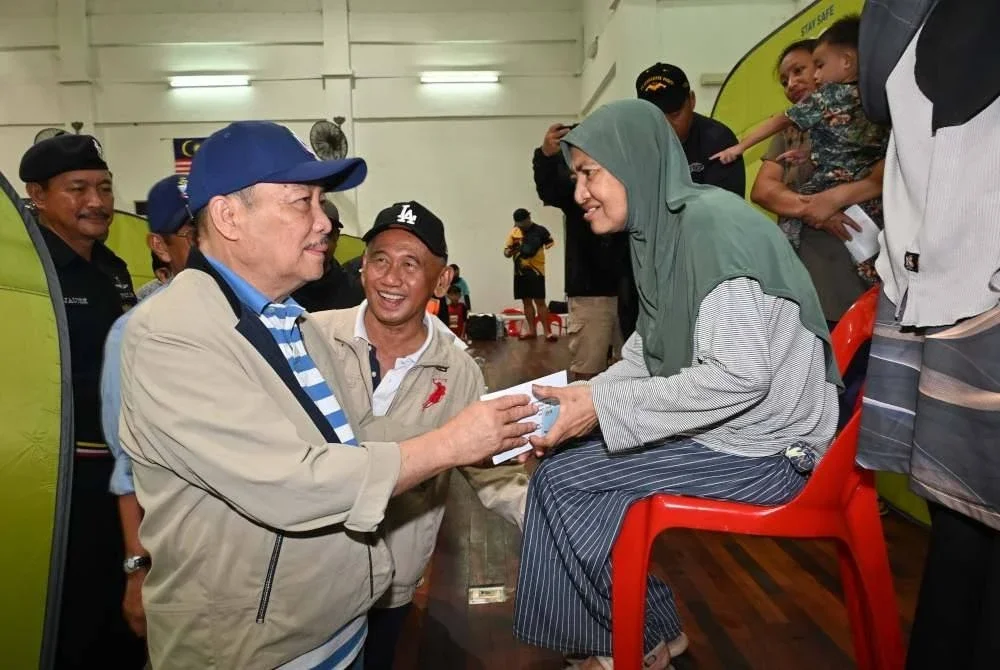 Hajiji menyerahkan bantuan kepada mangsa bencana banjir di PPS Dewan Sri Serigai, Putatan, Sabah pada Isnin. Foto Bernama