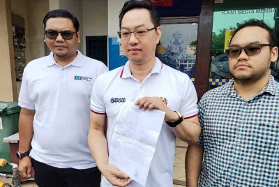 Jimmy (tengah), menunjukkan laporan polis yang dibuat.