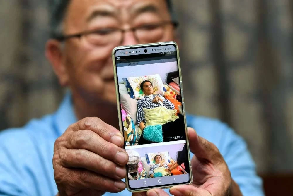 Sang menunjukkan gambar anaknya yang mengalami masalah kesihatan. Foto Bernama