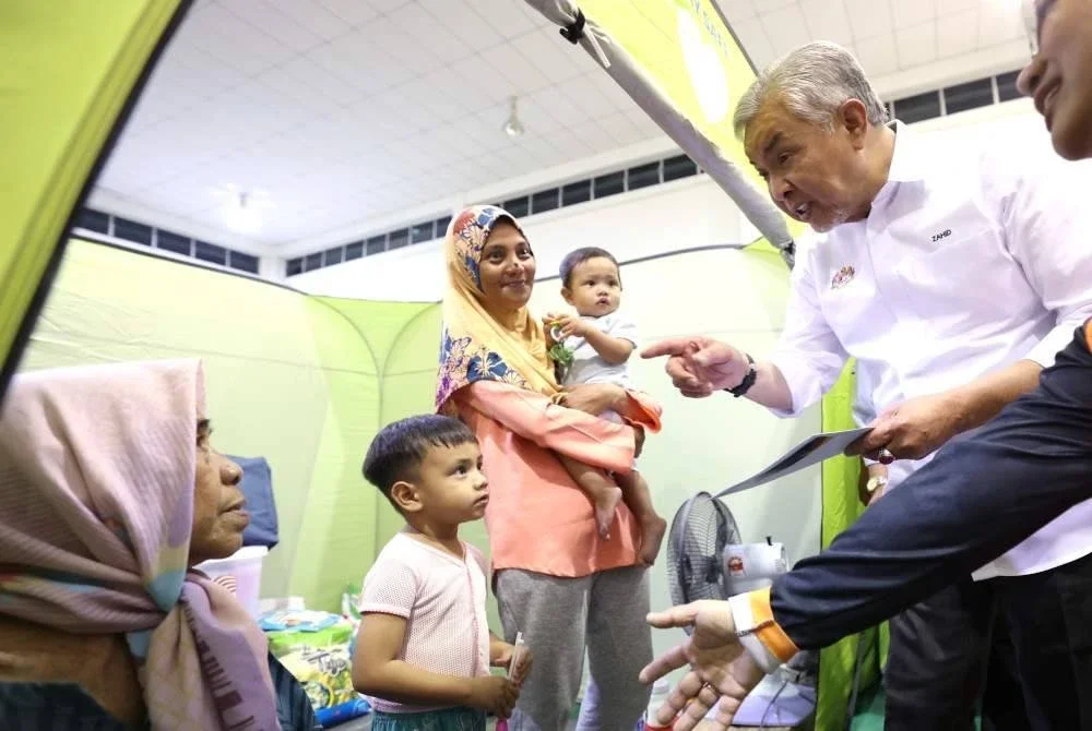 Ahmad Zahid menyantuni mangsa banjir di PPS Keramat Putatan pada Rabu. Foto Bernama
