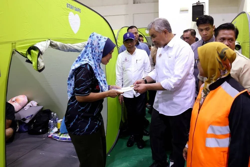 Ahmad Zahid menyantuni mangsa banjir di PPS Keramat Putatan pada Rabu. Foto Bernama