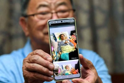 Sang menunjukkan gambar anaknya yang mengalami masalah kesihatan. Foto Bernama