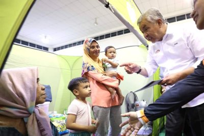 Ahmad Zahid menyantuni mangsa banjir di PPS Keramat Putatan pada Rabu. Foto Bernama