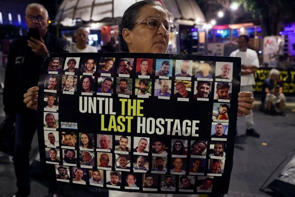 Plakad tertera gambar baki tawanan di Gaza dibawa salah seorang ahli keluarga yang terlibat demonstrasi itu.