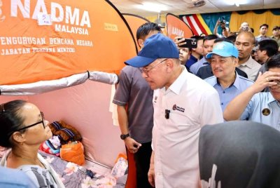 Anwar (tiga dari kanan) bersama Hajiji (dua dari kanan) ketika melawat mangsa banjir di PPS di Penampang pada Jumaat. Foto Sinar Harian