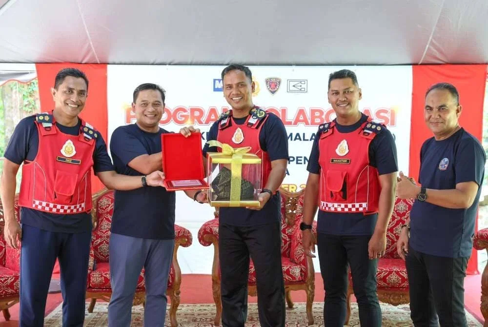 Nor Hisham (tengah) menerima cenderamata sempena Program Kolaborasi Gabungan Kelab Media Malaysia (GKMM) bersama JBPM di Hutan Lipur Sekayu di Hulu Terengganu pada Ahad.
