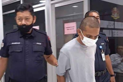 Tertuduh (tengah) ketika dihadapkan di Mahkamah Majistret dan Mahkamah Sesyen di Kuala Terengganu pada Ahad atas dakwaan terlibat aktiviti pengedaran dadah pada April lalu.