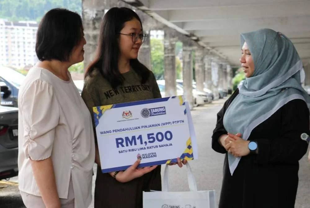 Norliza (kanan) menyantuni pelajar yang menerima WPP semasa sesi ziarah rumah ke rumah di kawasan Bukit Gelugor, Pulau Pinang.