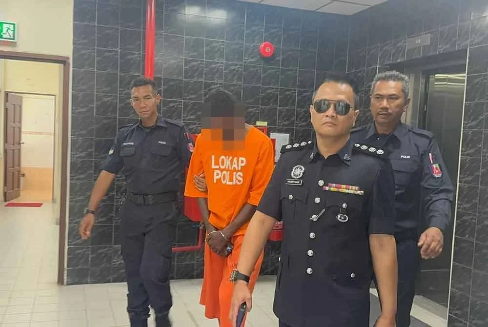 Suspek diiringi anggota polis ketika dibawa ke Mahkamah Butterworth pada Isnin.