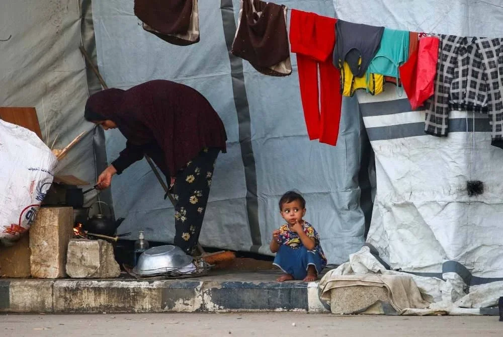 Penduduk Palestin yang dipaksa berpindah dari Bandar Gaza terpaksa mendirikan khemah sementara untuk berlindung di tepi jalan. Foto AFP
