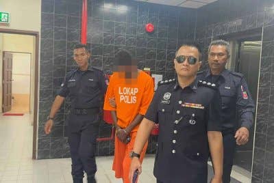 Suspek diiringi anggota polis ketika dibawa ke Mahkamah Butterworth pada Isnin.