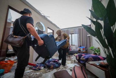 Mangsa Fazeela Yaccob bersama ahli keluarganya mengalihkan barangan yang rosak selepas bahagian bumbung rumahnya diterbangkan angin selepas kejadian ribut di PPR Seri Cempaka petang Isnin. Foto Bernama