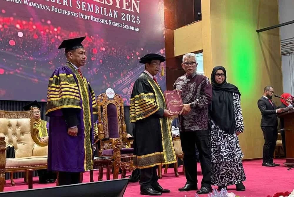 Muhamad Rizal (dua kanan) bersama isteri naik le pentas bagi menerima Sijil Teknologi Seni Bina anaknya sempena Majlis Konvokesyen Kolej Komuniti Negeri Sembilan pada Selasa.