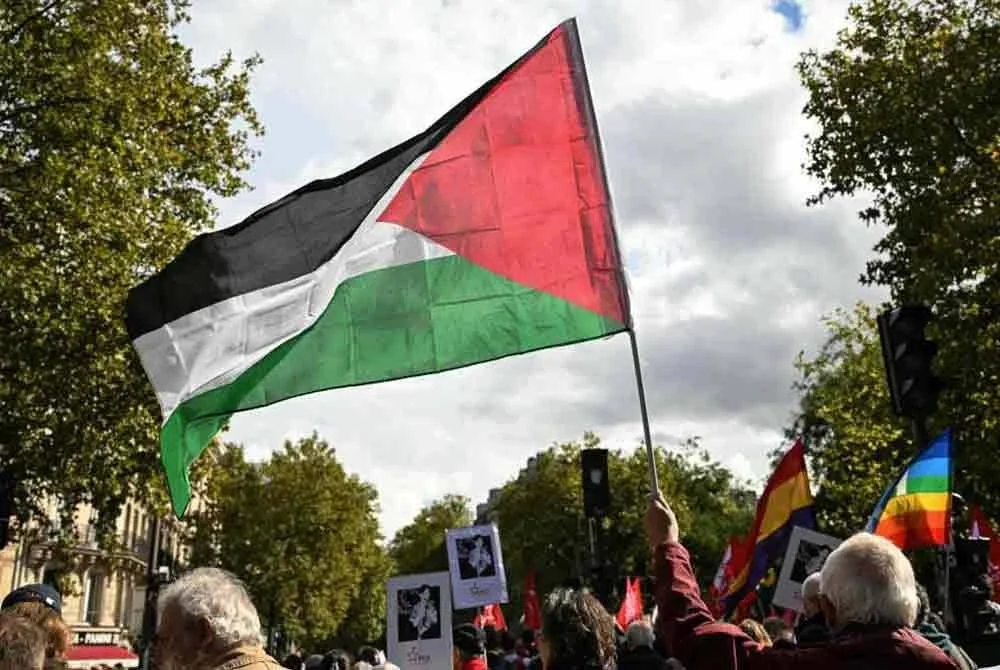 Seorang penunjuk perasaan mengibarkan bendera Palestin semasa menyertai perarakan yang menuntut pengiktirafan negara Palestin dan penghentian pembunuhan beramai-ramai di Paris pada 21 September 2025. Foto AFP