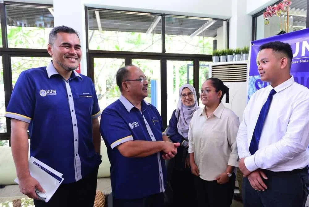 Mohd Foad (dua dari kiri) beramah mesra bersama beberapa pelajar yang mendaftar masuk UUM pada Selasa.