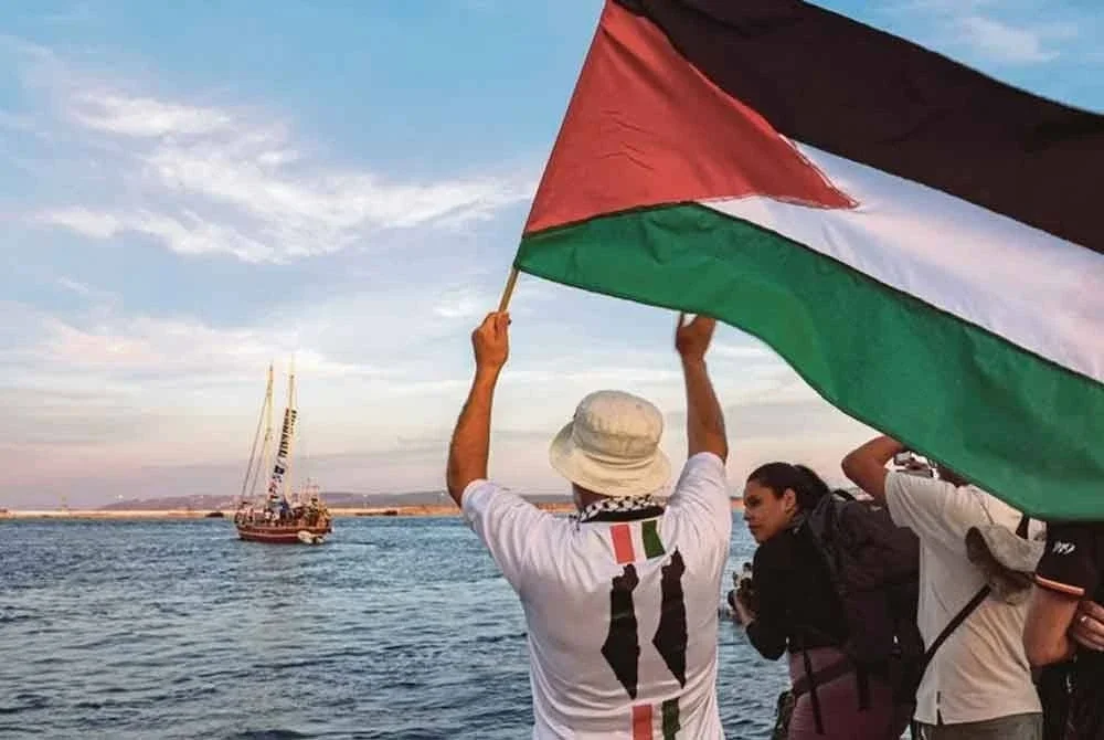 Aktivis mengibarkan bendera Palestin ketika beberapa kapal yang menyertai misi Global Sumud Flotila berlepas dari Pelabuhan Tunisia 14 September lalu. Foto AFP