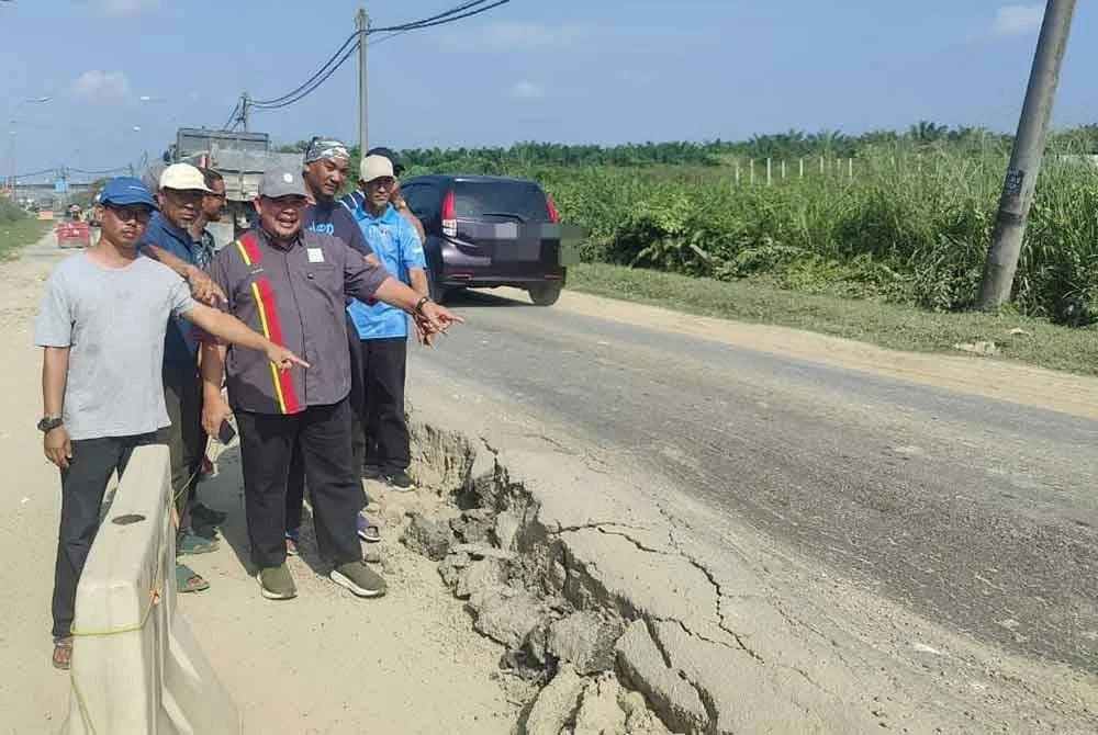 Noor Najhan (depan kanan) dan penduduk menunjukkan keadaan mendapan tanah di Jalan Iskandar di sini.