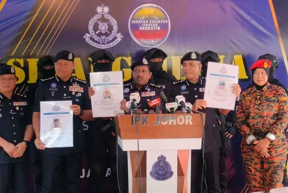 Hussein menunjukkan gambar suspek yang dikehendaki polis berhubung pembongkaran dua buah makmal haram memproses dadah di sekitar Senai.