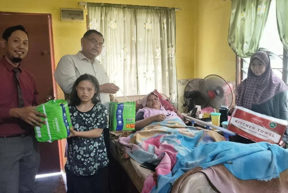 Nur Amalina (kanan) setia menjaga ibu dan adiknya di rumah mereka di Kampung Tanjung Langsat.