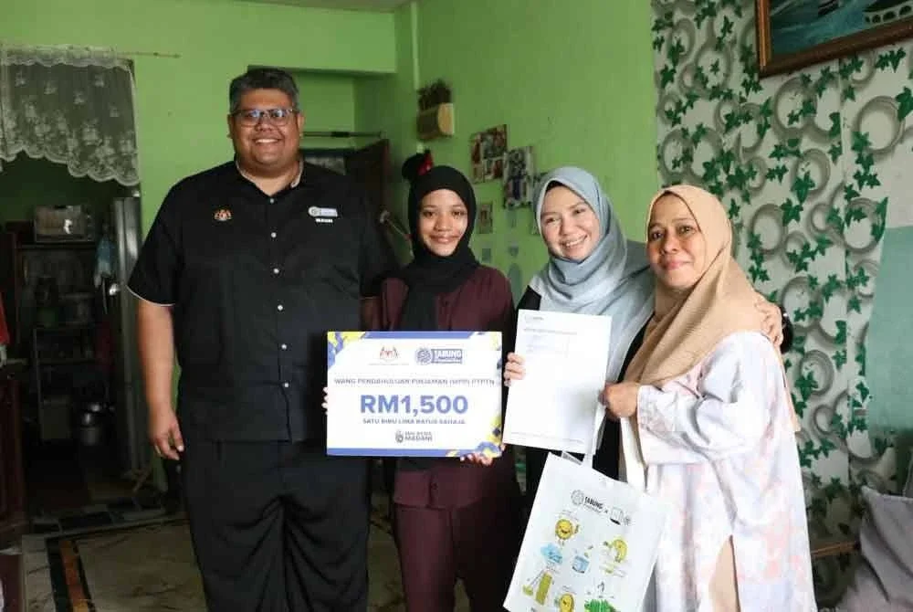 Norliza (dua dari kanan) menyerahkan replika kad WPP berjumlah RM1,500 kepada seorang pelajar di Pulau Pinang.