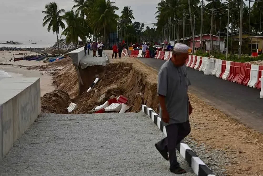 Beberapa penduduk meninjau lokasi jalan yang runtuh pada pagi Khamis.