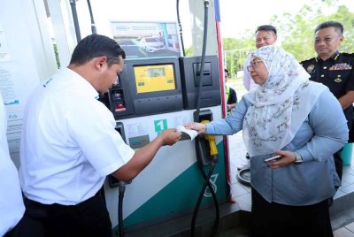 Fuziah diberi penerangan mengenai penggunaan SKPS ketika melakukan tinjauan persiapan sistem tersebut di Stesen Petronas Penampang 1 hari ini. Foto Bernama