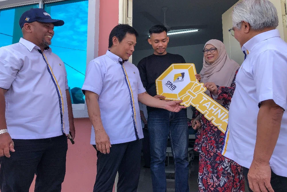 Pengerusi Syarikat Perumahan Negara Berhad (SPNB) Datuk Prof Dr Mohd Azmi Mohd Lila (dua, kiri) menyerahkan replika kunci kepada mangsa tragedi kebakaran rumah Muhamad Zulhaidi Mispar, 27, (tengah) pada Program Penyerahan Rumah Mesra Rakyat di Tanjong Karang hari ini. Foto Bernama 
