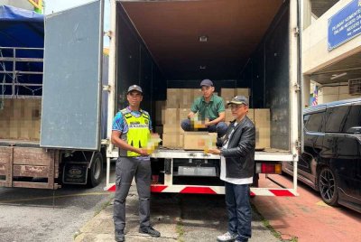 Azman (kanan) memeriksa minyak masak ditemukan dalam dua lori yang telah dirampas. FOTO SINAR HARIAN - ADILA SHARINNI WAHID