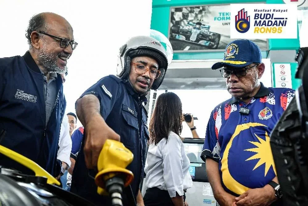 Saifuddin Nasution (kanan) beramah mesra dengan anggota polis ketika menyaksikan warga PDRM menikmati subsidi petrol RON95 menerusi BUDI95 di Daerah Sandakan pada Sabtu. Foto Bernama
