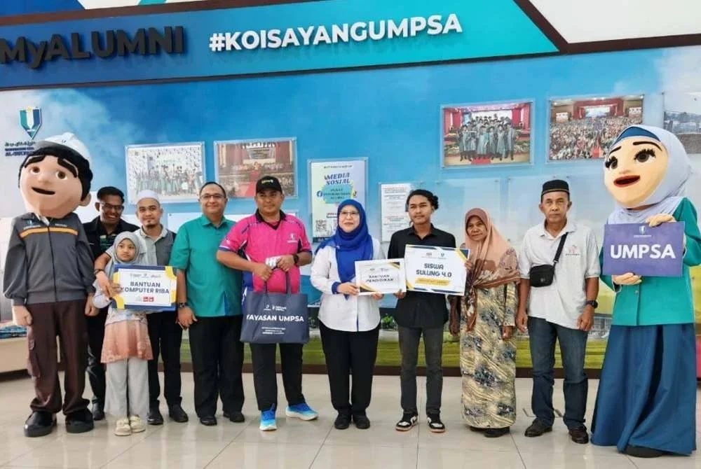 Dr Yatimah menyampaikan insentif bantuan pendidikan Yayasan Perkasa Siswa KPT, Biasiswa Sulung dan komputer riba kepada Muhammad Afiq semasa menyantuni pelajar itu di UMPSA Pekan pada Sabtu. Foto UMPSA