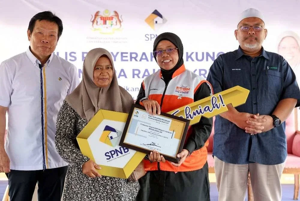 Aiman Athirah (dua dari kanan) menyerahkan kunci Rumah Mesra Rakyat (RMR) kepada pekerja lanskap, Mazrina Mohd Dahab@Haidu, 50, pada Majlis Penyerahan Kunci RMR di Rancangan Tanah Berkelompok (RTB) Kampung Baru Kiri, Kemasik, Kerteh hari ini. Foto: Bernama