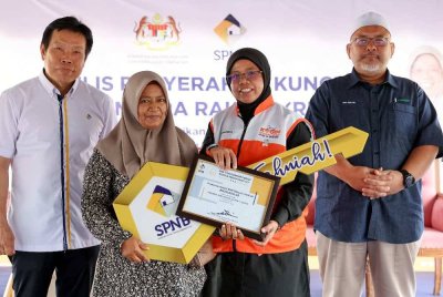 Aiman Athirah (dua dari kanan) menyerahkan kunci Rumah Mesra Rakyat (RMR) kepada pekerja lanskap, Mazrina Mohd Dahab@Haidu, 50, pada Majlis Penyerahan Kunci RMR di Rancangan Tanah Berkelompok (RTB) Kampung Baru Kiri, Kemasik, Kerteh hari ini. Foto: Bernama